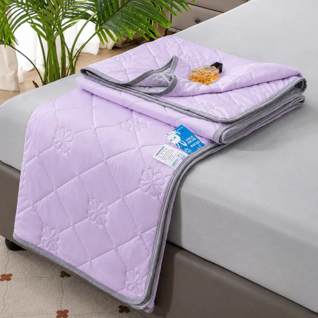 Purple quilted blanket folded on a bed, folded corner showing gray trim and a fabric care tag.