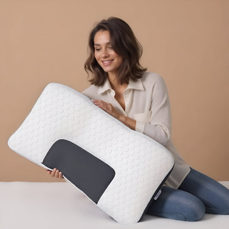 Woman kneeling on a bed while holding the contour pillow.