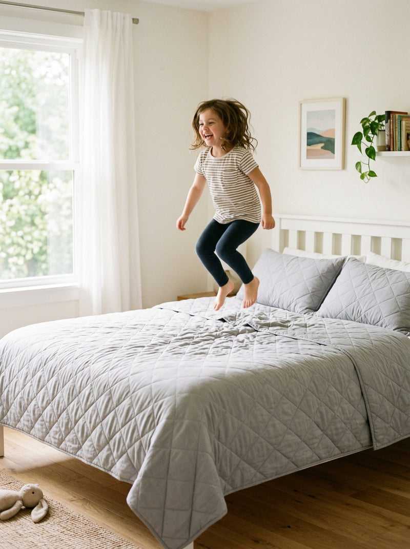 Child jumping onto a bed with DreamWrap in Light Grey
